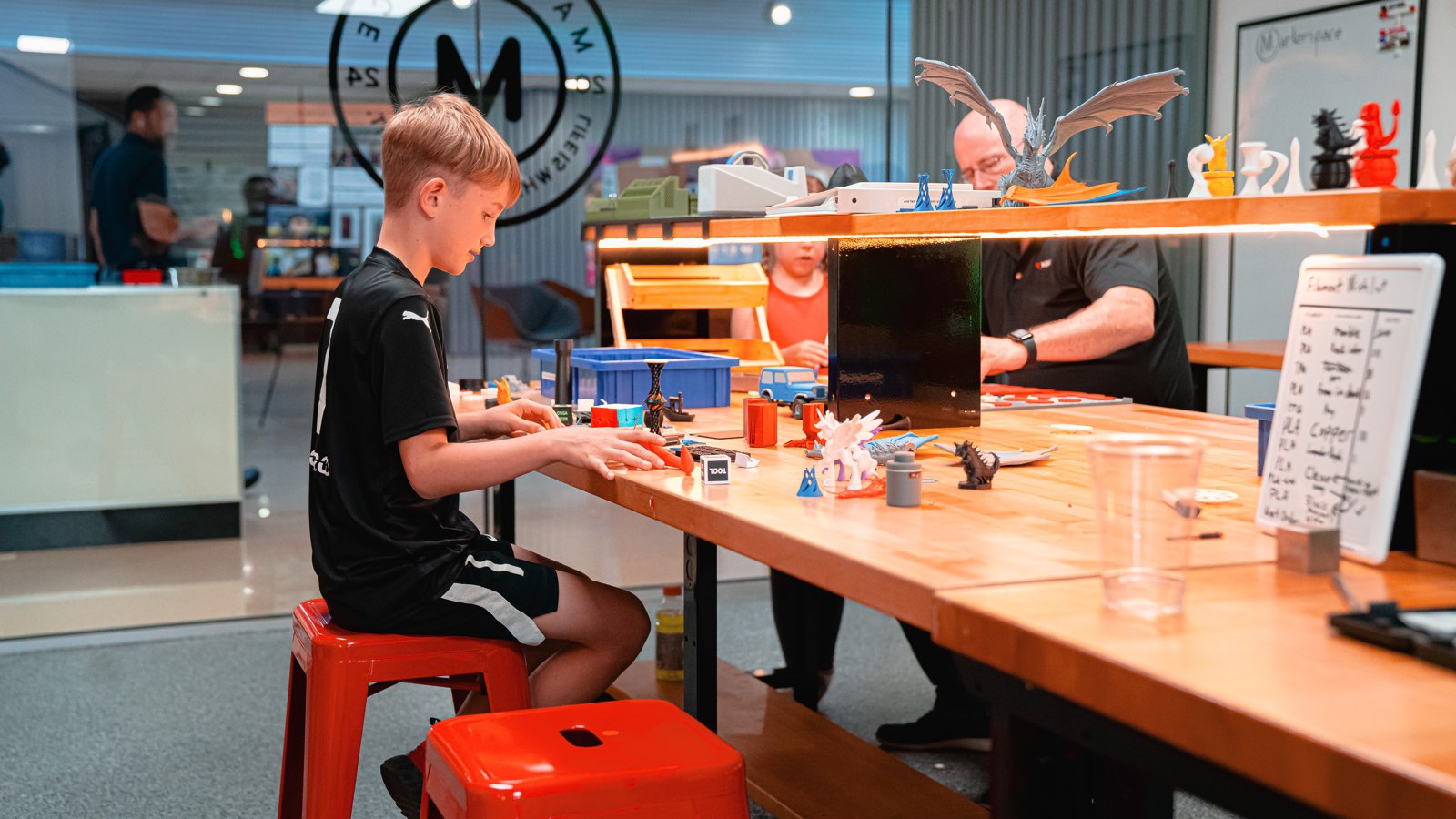 A boy building at the 3D Lab bench under the Makerspace logo
