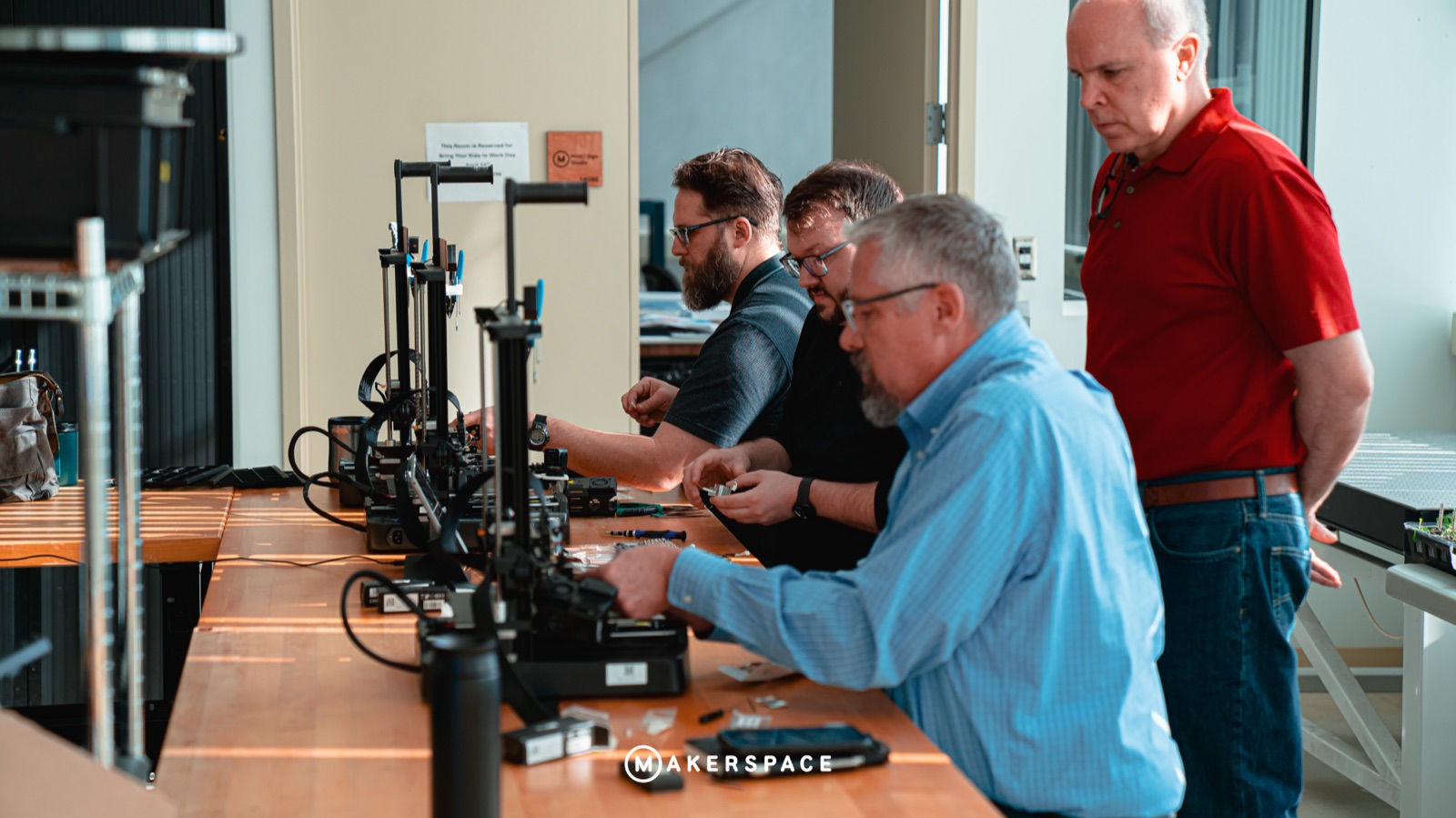 Group of makers repairing a 3D printer together