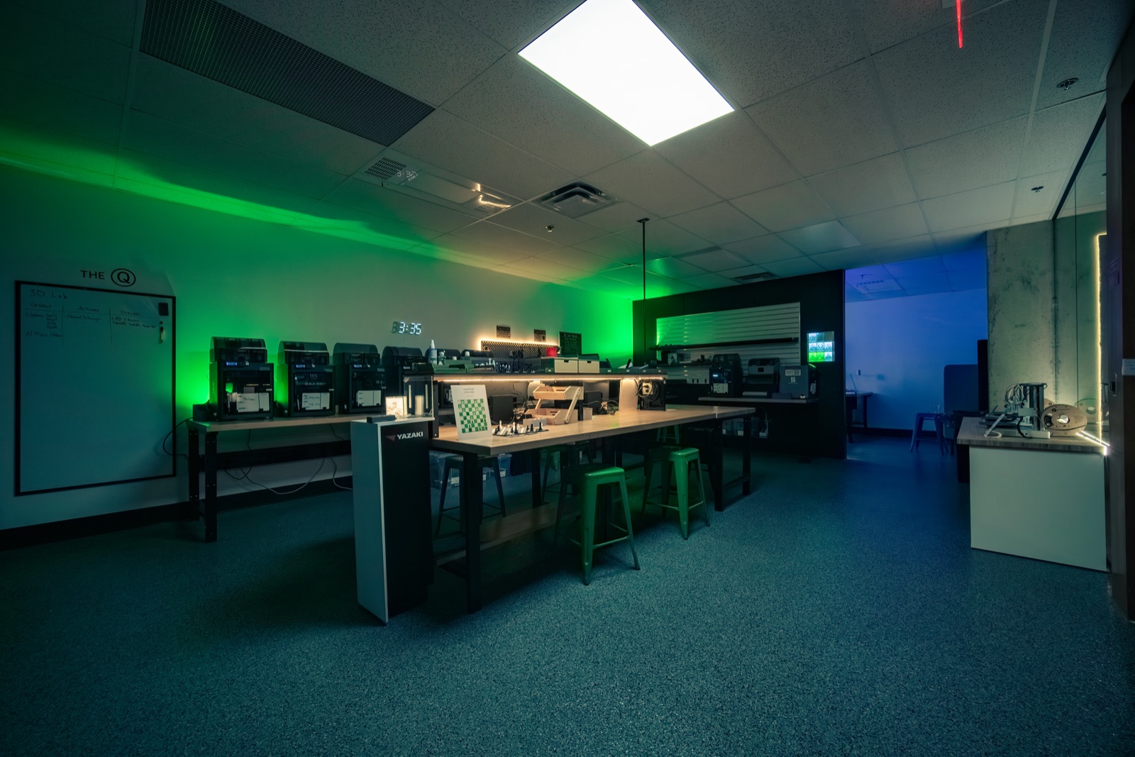 Row of 3D printers under green light in the Makerspace 3D Lab